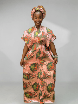 Coral pink and green floral brocade gown with woven textured pattern and adjustable waist ties on grey studio background