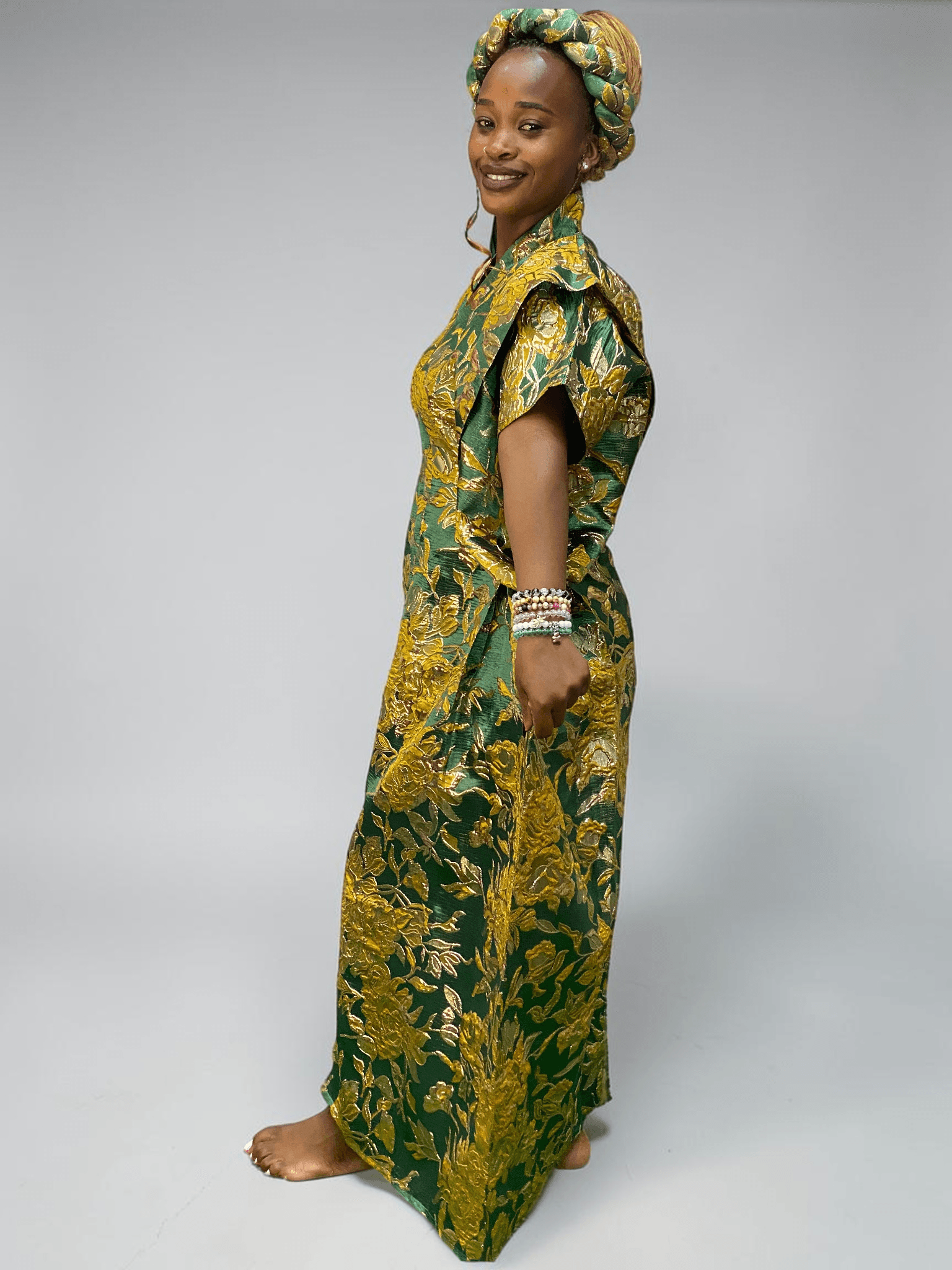 Emerald green and gold floral brocade gown with woven textured pattern and adjustable waist ties on grey studio background