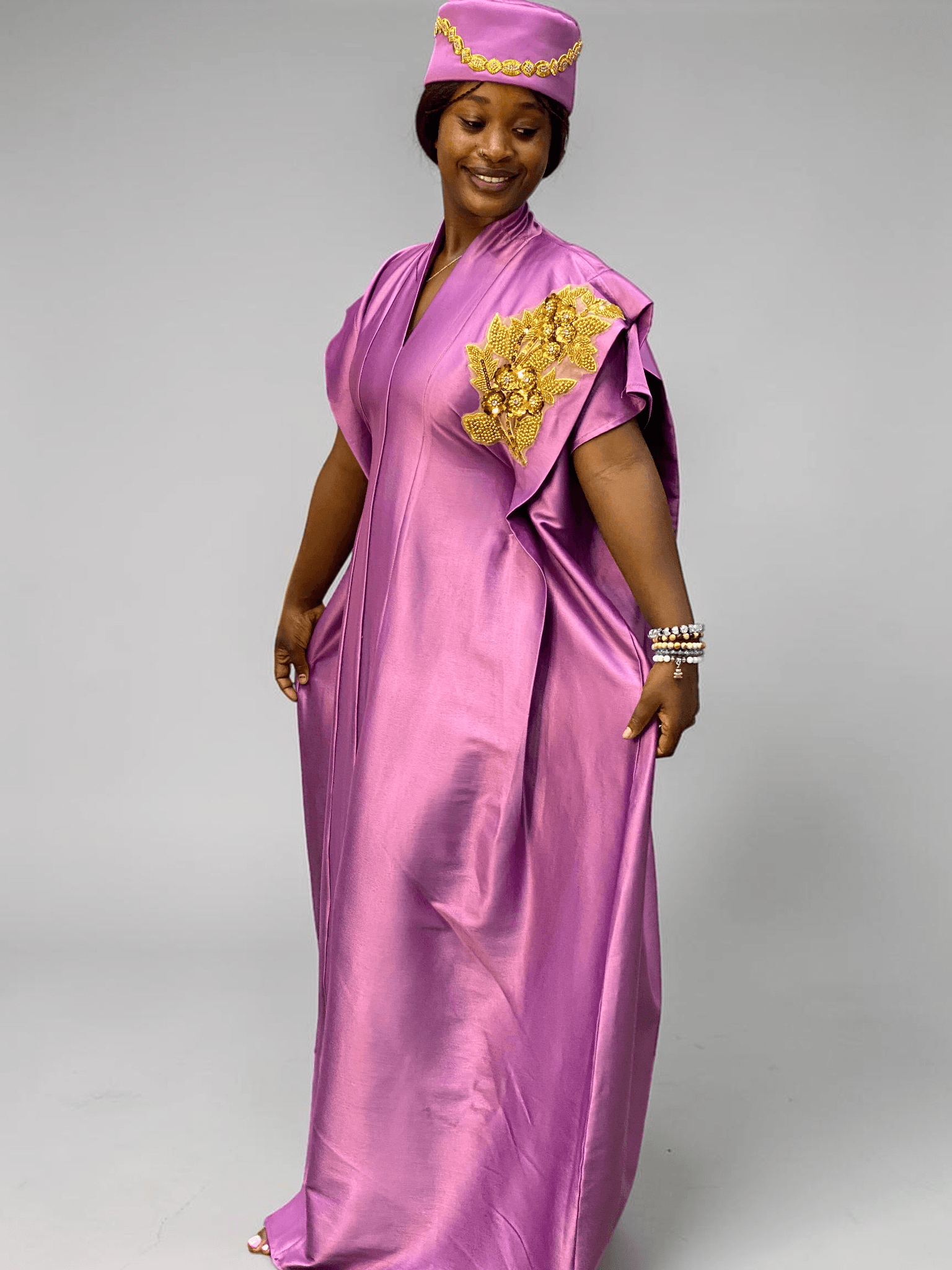 Orchid purple satin boubou gown with embellished shoulder detail and adjustable waist ties on grey studio background
