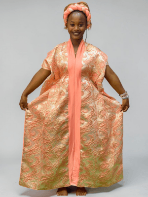 Peach and gold brocade gown with woven textured pattern and adjustable waist ties on grey studio background
