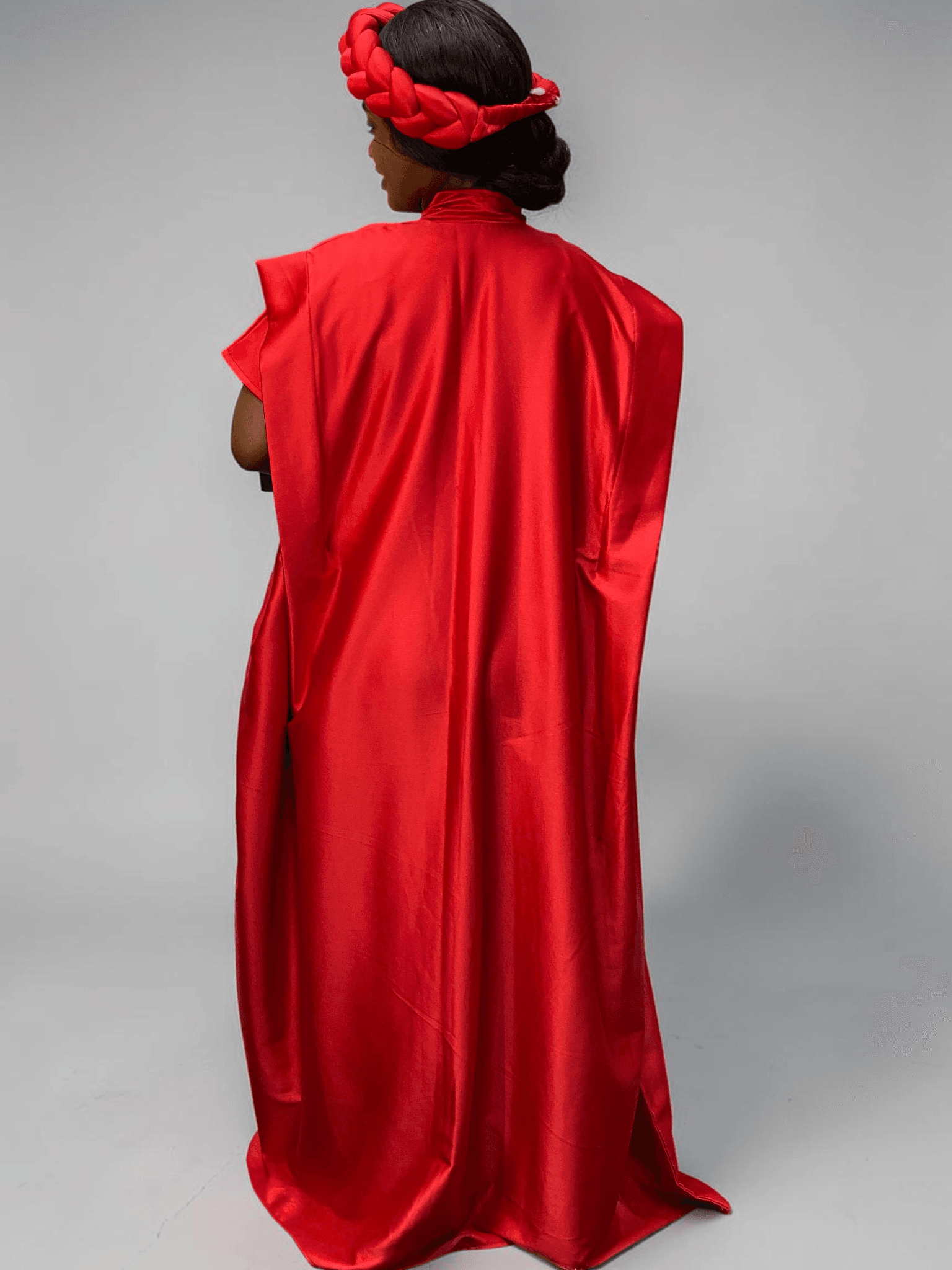 Crimson red satin boubou gown with wide sleeves and adjustable waist ties on grey studio background