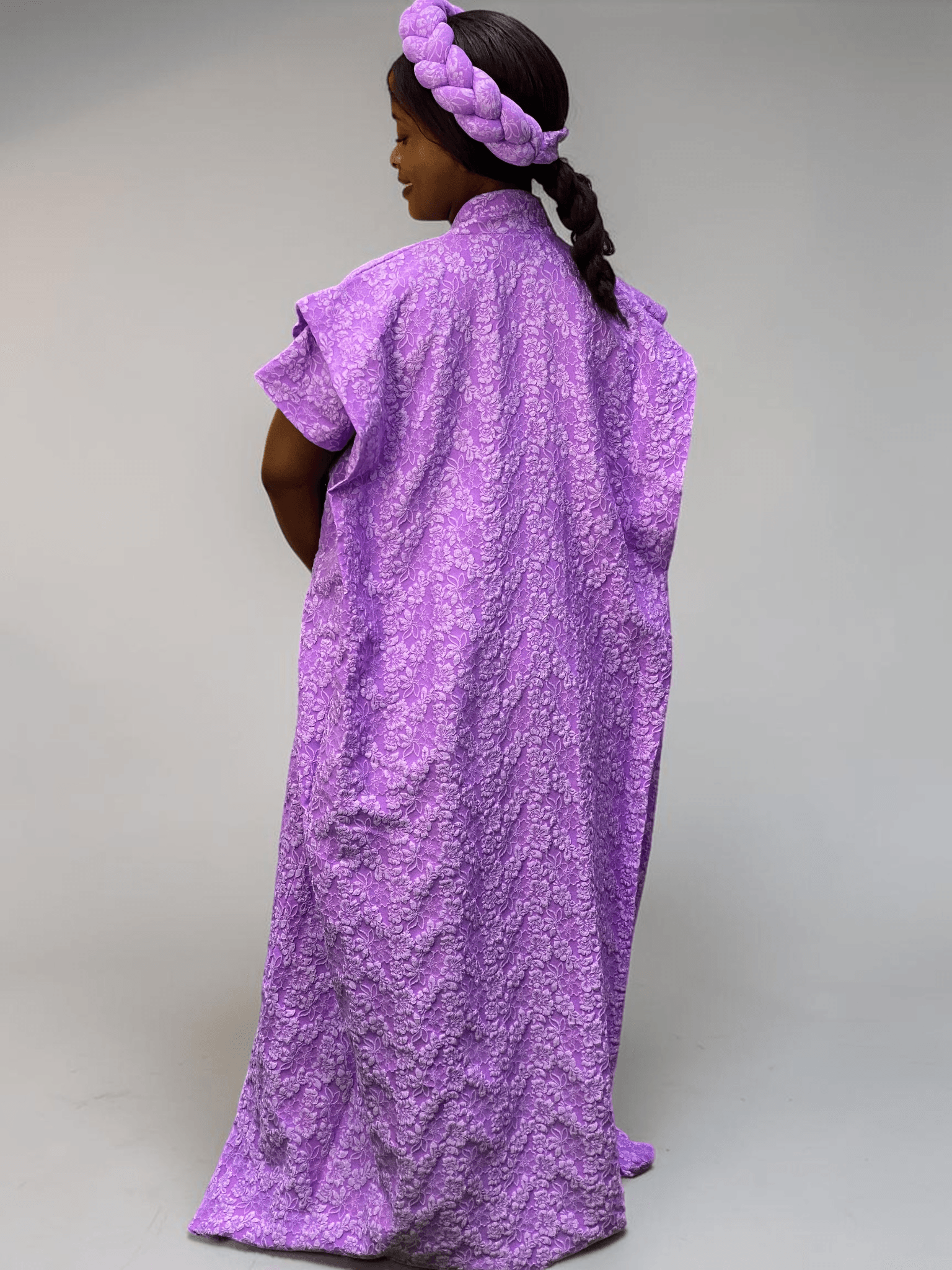Lavender purple 3D floral gown with raised floral texture and adjustable waist ties on grey studio background