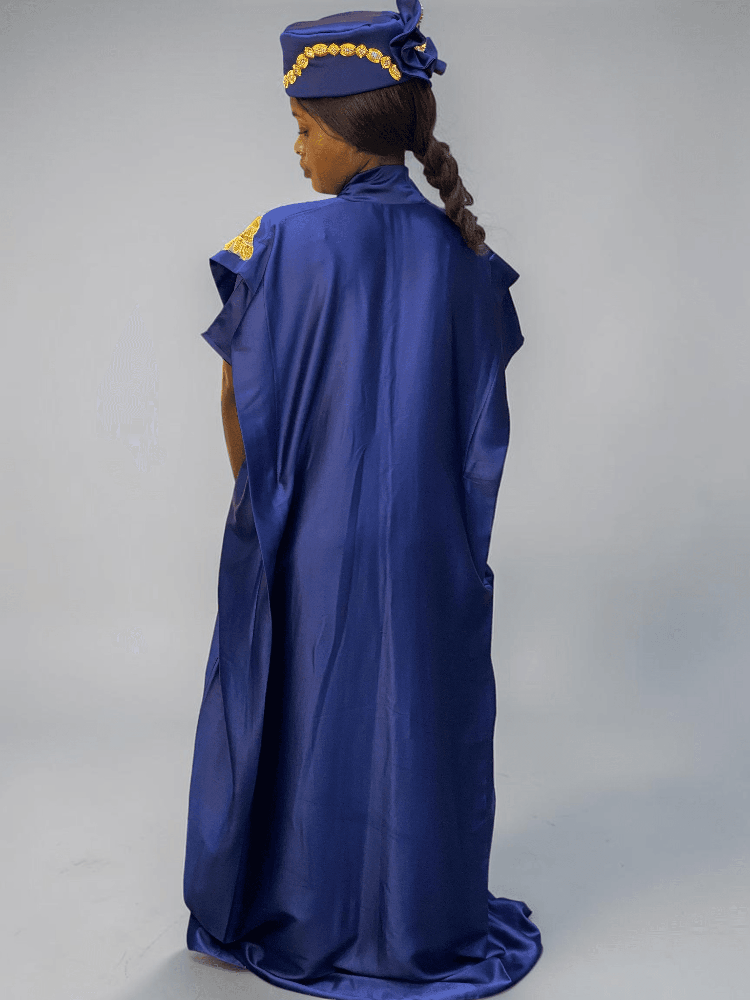 Royal blue satin boubou gown with embellished shoulder detail and adjustable waist ties on grey studio background