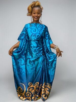 Turquoise blue printed satin kaftan with scroll artwork and adjustable waist ties on a grey studio background