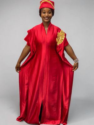 Ruby red satin boubou gown with embellished shoulder detail and adjustable waist ties on grey studio background