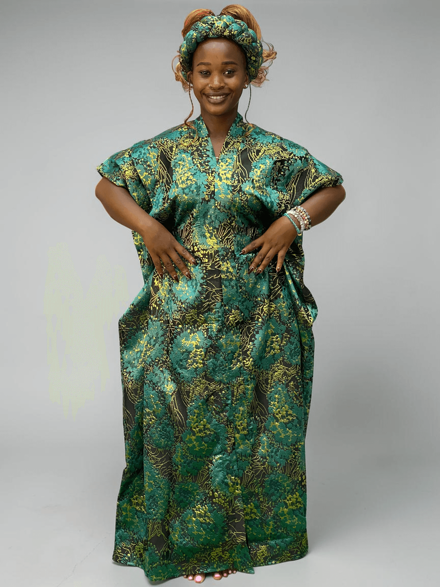 Teal green and gold floral brocade gown with woven textured pattern and adjustable waist ties on grey studio background