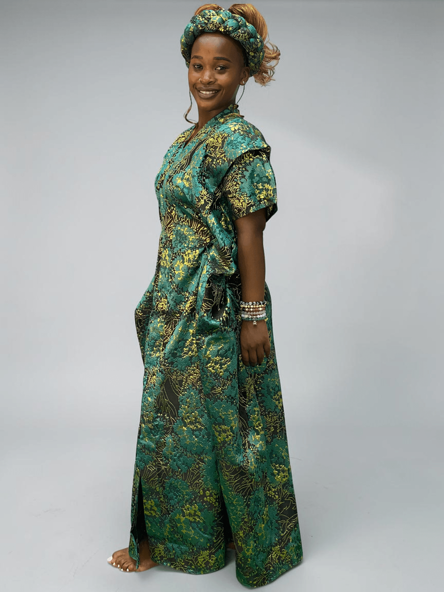 Teal green and gold floral brocade gown with woven textured pattern and adjustable waist ties on grey studio background