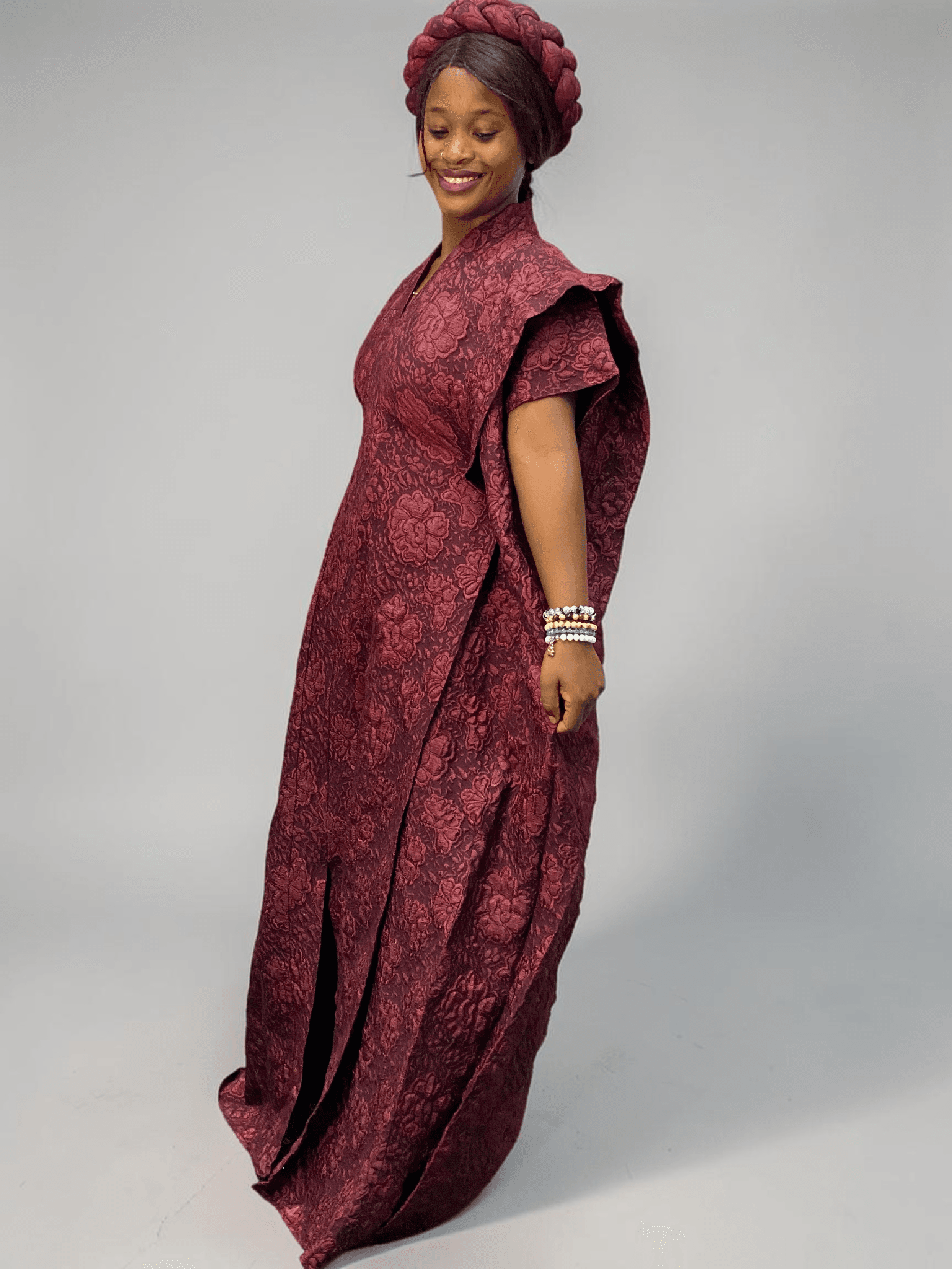 Burgundy 3D floral gown with raised floral texture and adjustable waist ties on grey studio background