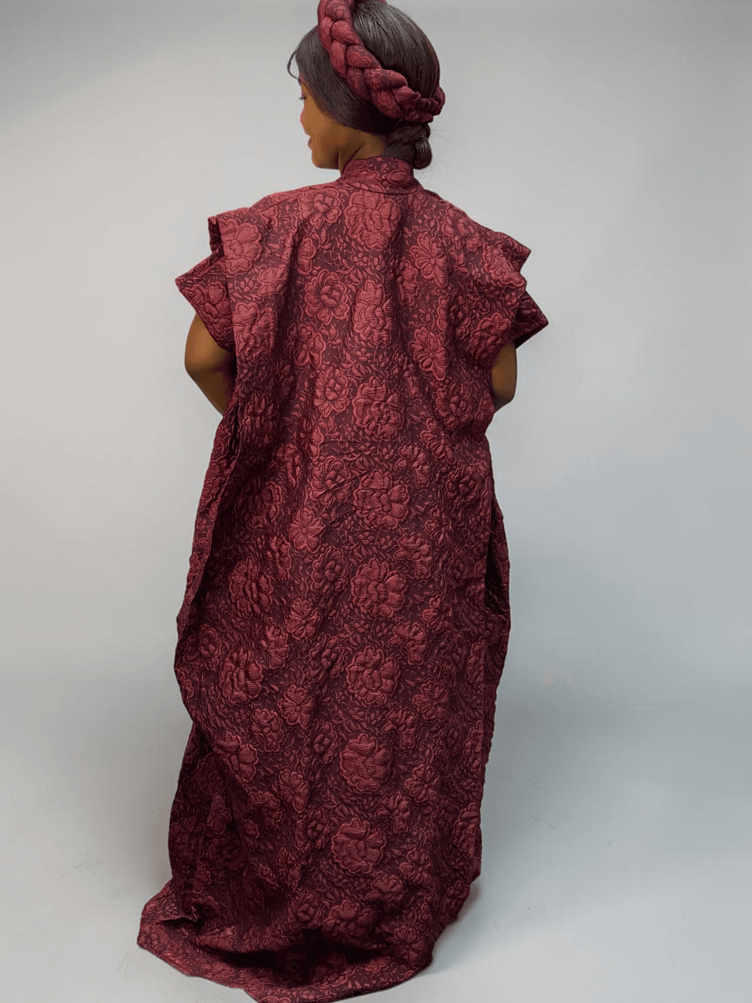 Burgundy 3D floral gown with raised floral texture and adjustable waist ties on grey studio background